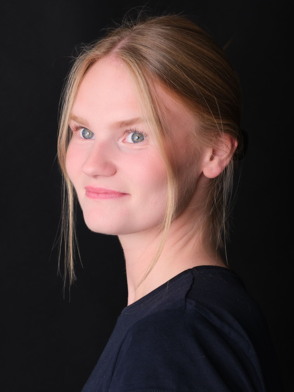 Porträtt av Rebecka Norling i mörk tröja mot svart bakgrund, blicken mot kameran